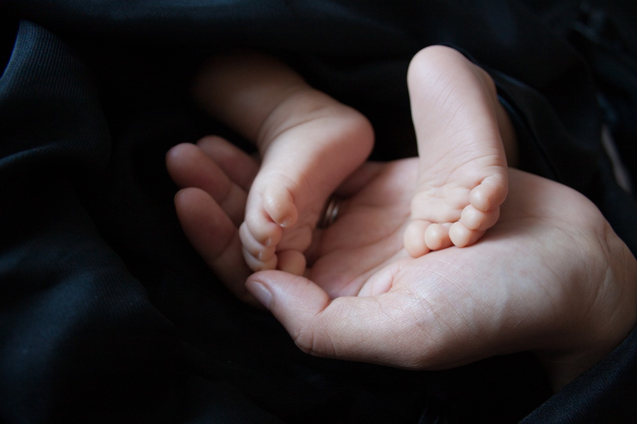 adult hand holding infant's feet